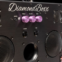 zoomed in view of diamondboxx logo, power, and tws buttons on the front of black M3 speaker with purple knobs